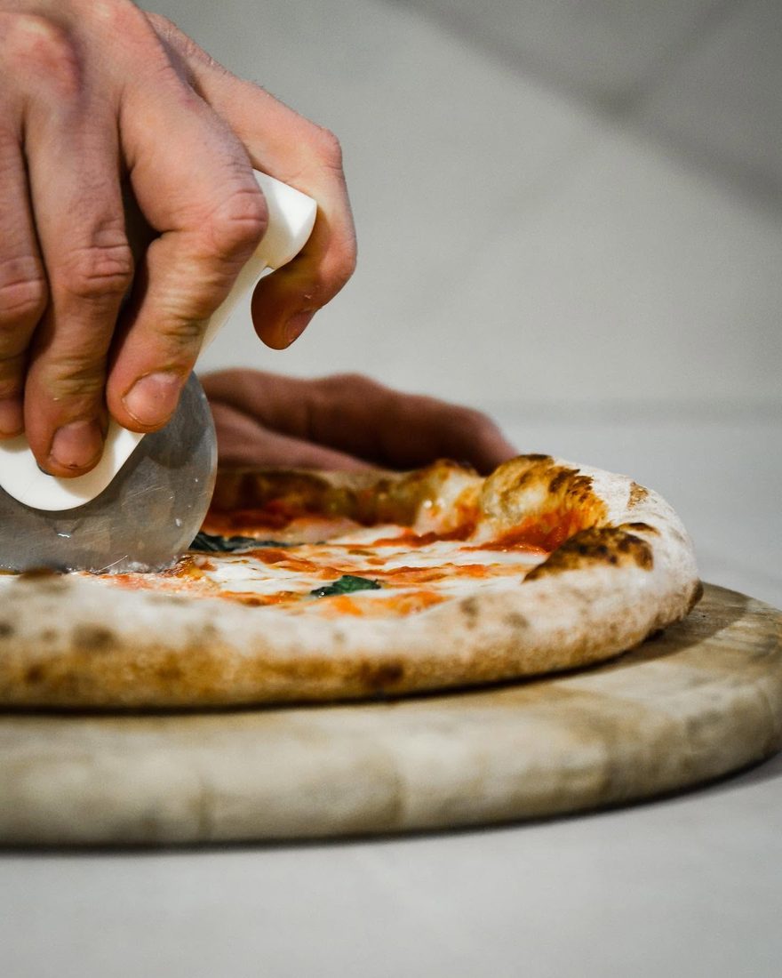 Una Margherita appena sfornata tagliata a spicchi con la rotella